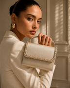Model in ivory blazer looking back over her shoulder holding Bare Silk crystal-embellished mini top-handle bag by House of Shine, gold hoop earrings, gold-polished hardware, saffiano exterior, Bijou Edit.