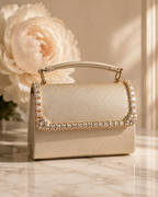 Bare Silk crystal-embellished mini top-handle bag by House of Shine, styled against a blush peony on marble, gold-polished hardware, saffiano exterior, Bijou Edit.