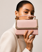 Blush pink crystal-trimmed mini top handle bag held up to face by model in ivory blazer, The House of Shine Bijou Edit