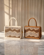Boho hand-beaded satchel by House of Shine in both colourways — Ivory and Caramel butter suede with rose gold and silver chevron beading, side by side on white marble surface in warm window light