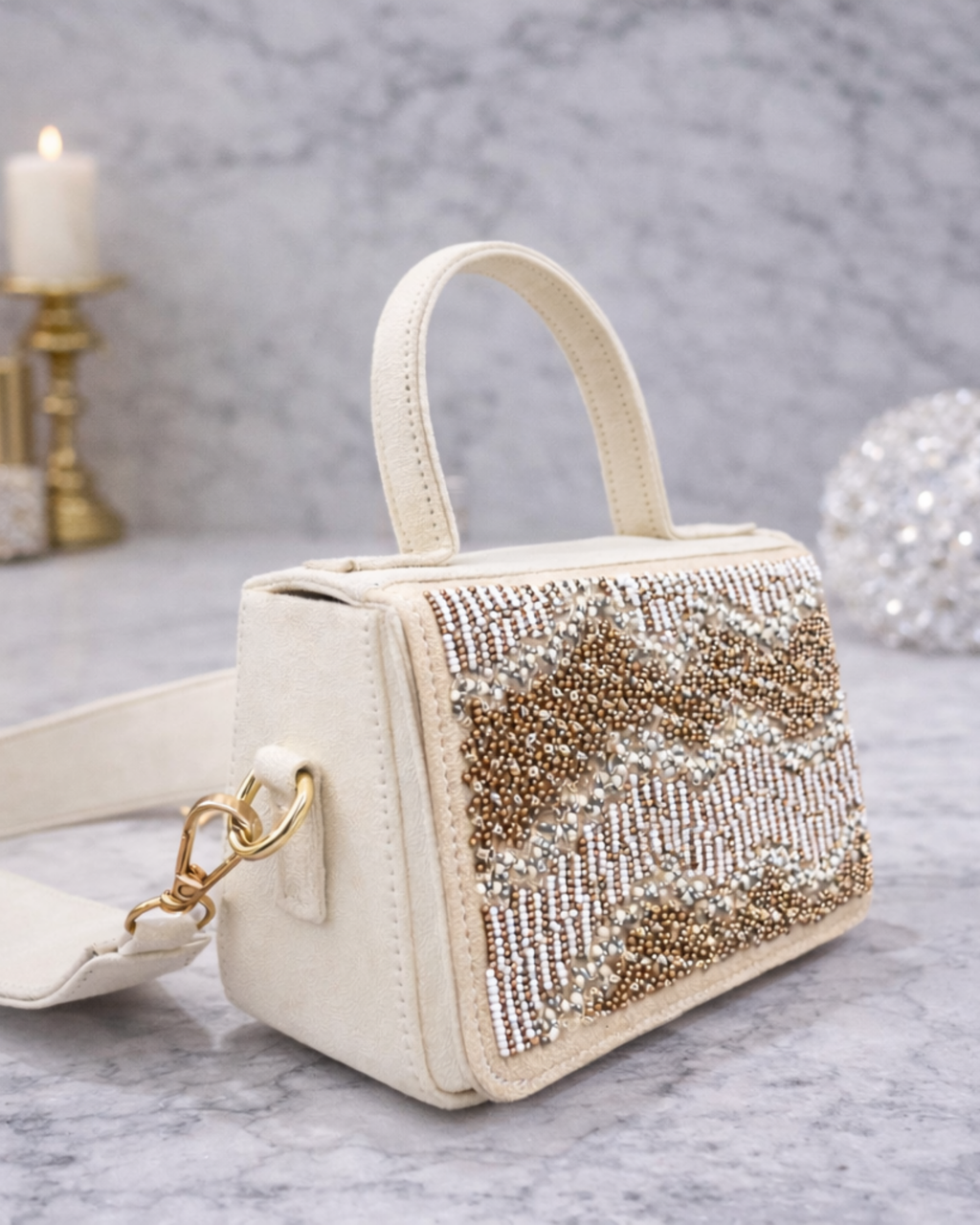 Boho hand-beaded ivory butter suede satchel by House of Shine side view with rose gold and silver beading on marble surface.