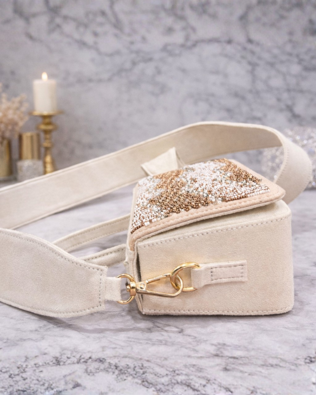 Boho ivory satchel by House of Shine showing wide suede crossbody strap open flap and gold clip hardware on marble.