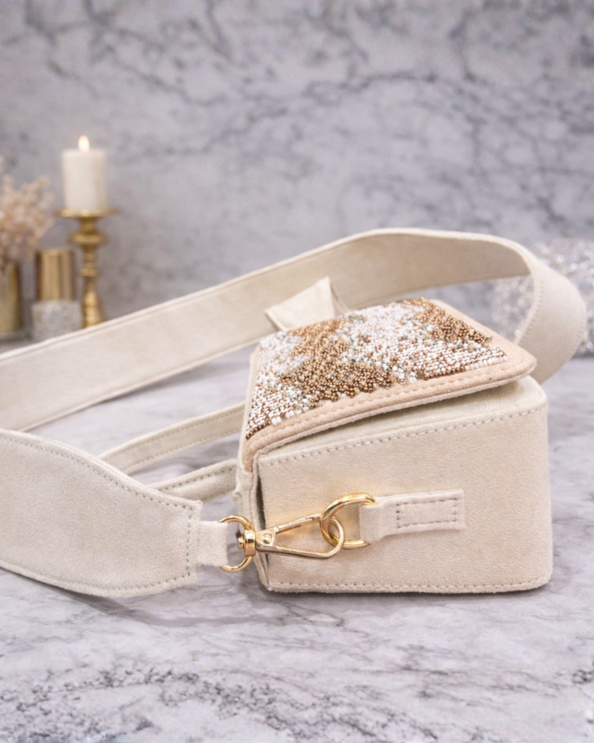 Boho ivory satchel by House of Shine showing wide suede crossbody strap open flap and gold clip hardware on marble.