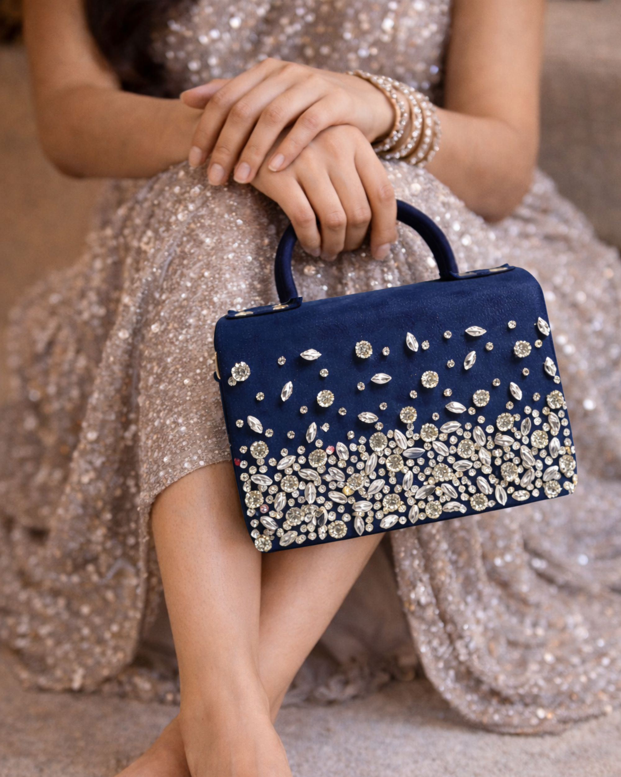 Model in gold sequin lehenga holding Estrella midnight navy rhinestone satchel by House of Shine as top handle bag with gold bangles