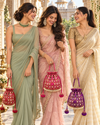 Three women in sarees carrying Gulnaar Bandhej potli bags in red, pink and purple.