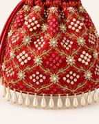 Close-up of red Gulnaar Bandhej fabric with gold beadwork, pearl clusters and dangling pearl-drop edging.