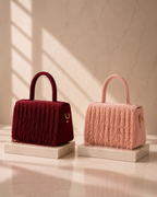 Maroon and blush Cascade Satchels displayed side by side on marble pedestals