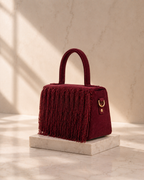 Maroon Cascade Satchel with beaded fringe embroidery, side profile on marble