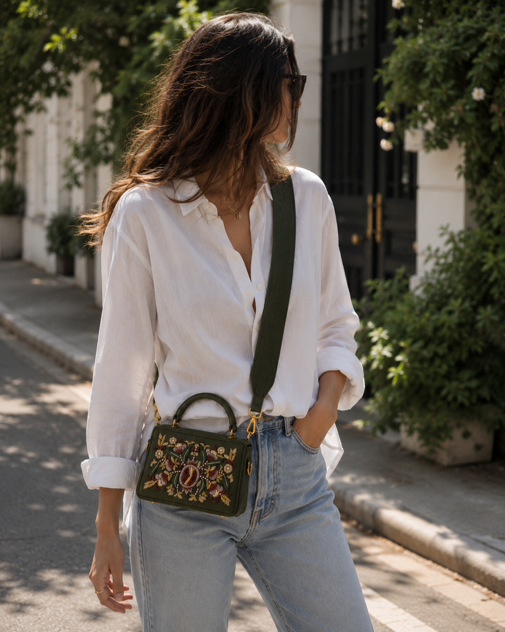 Model wearing The House of Shine Florence hand-embroidered olive satchel as a crossbody with wide strap, styled with white shirt and jeans outdoors
