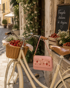 Fragola hand embroidered designer handbag hanging from a bicycle basket filled with strawberries