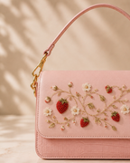 Close-up of Fragola's hand embroidered strawberry and daisy motif on pink leather handbag flap