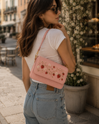 Woman wearing the Fragola pink embroidered shoulder bag with strawberry motif, street style