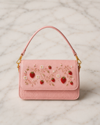Fragola pink hand embroidered bag with strawberry and floral motif, studio product shot on marble