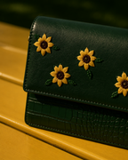 Close-up of Girasole showing hand-embroidered yellow floral motifs, green beadwork and crocodile-textured detailing.