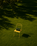 Girasole Mini Gelato green embroidered bag with yellow floral motifs displayed on a yellow chair in a sunlit garden.