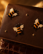 Close-up of handcrafted bee embroidery on the Miele chocolate brown mini bag by The House of Shine, featuring ivory, amber and black threadwork.