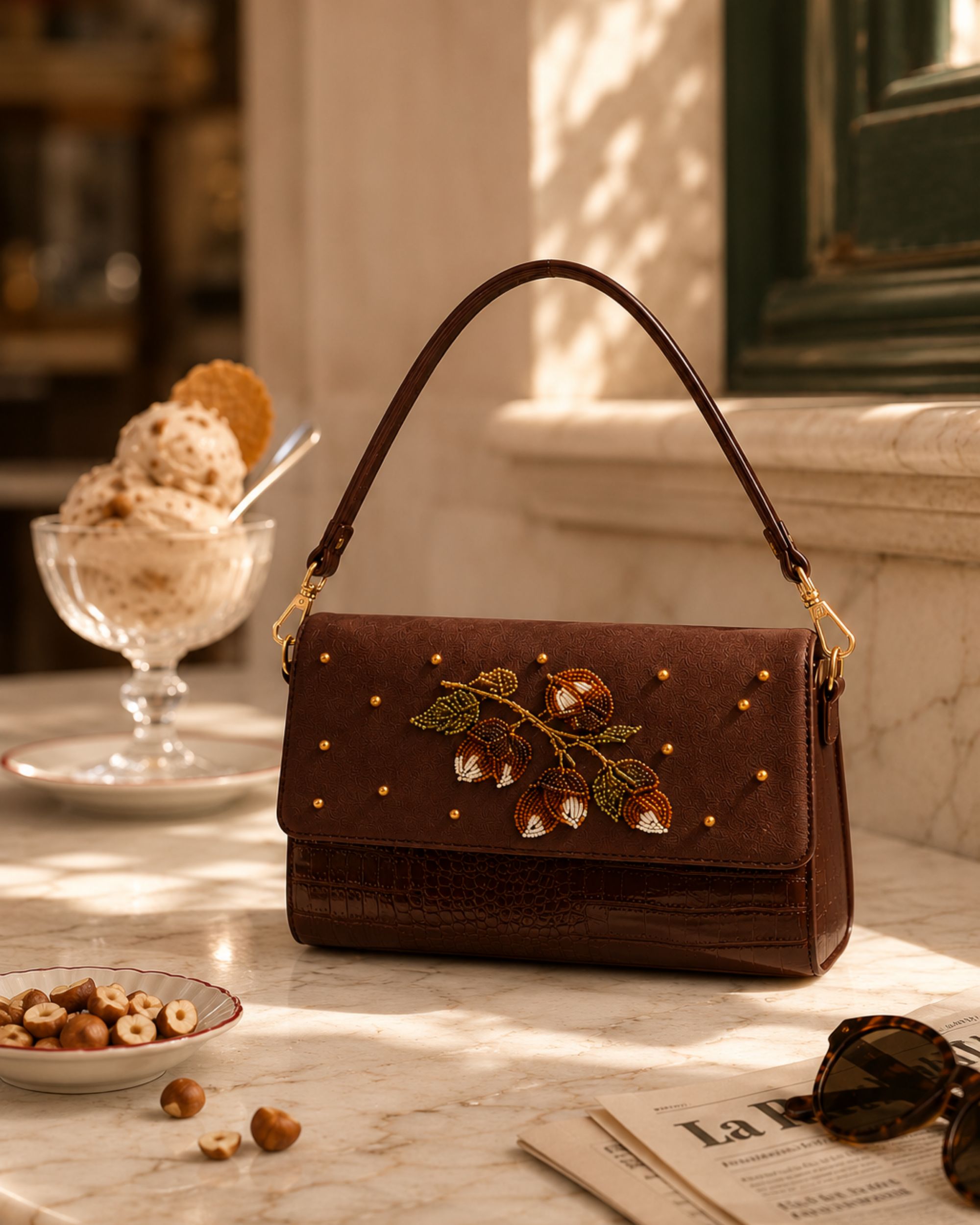 Hand embroidered bag India — The Nocciola bag detail beside scattered hazelnuts and gelato