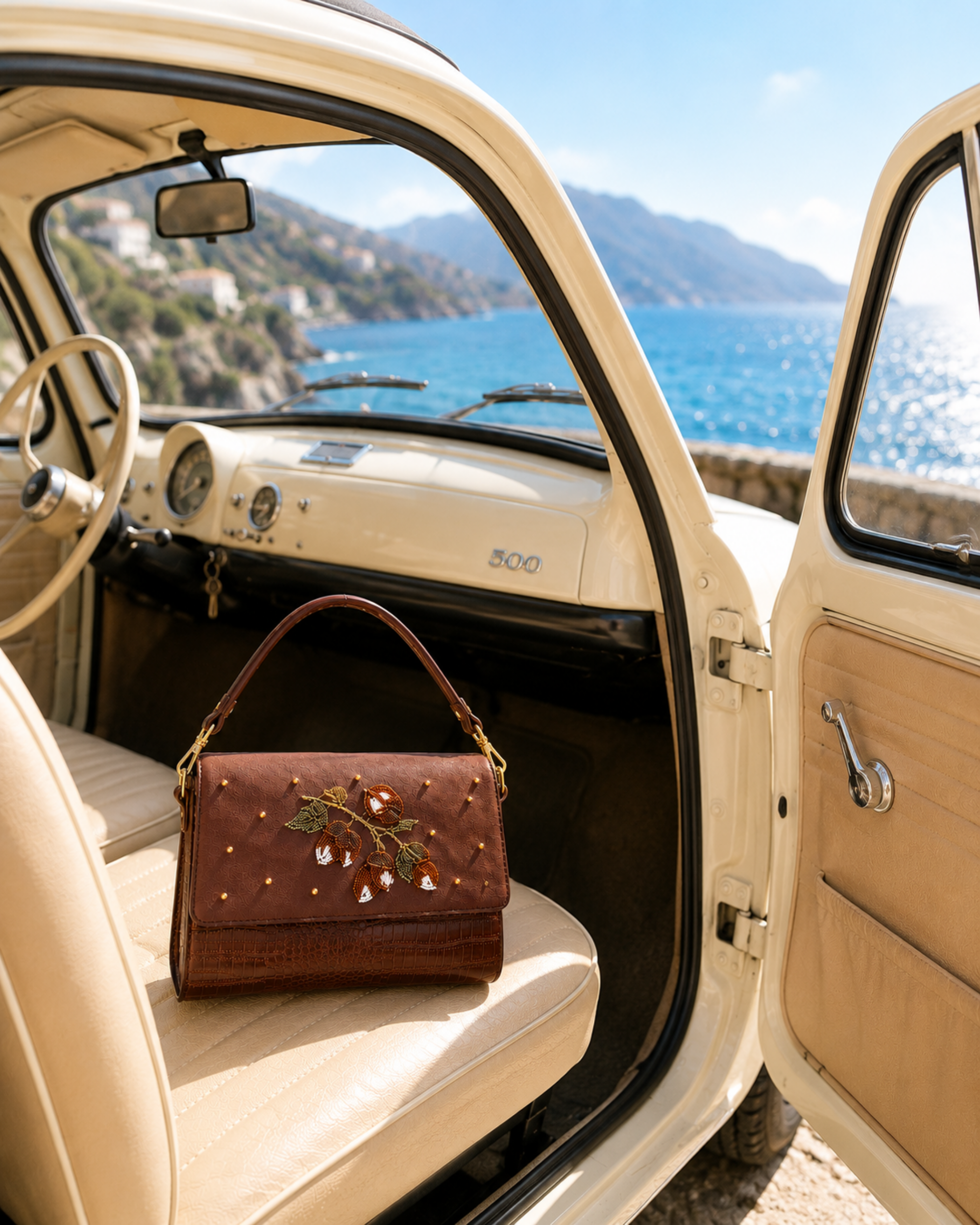 Luxury handbag India — The Nocciola structured shoulder bag on a vintage car seat with Amalfi coastline in view