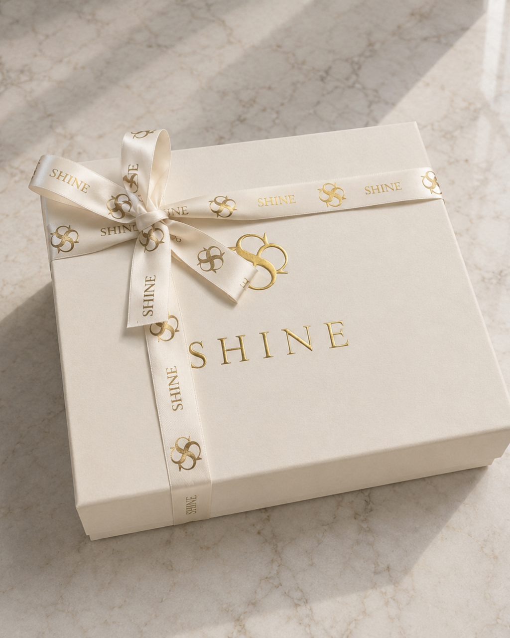 House of Shine ivory signature gift box with gold logo and branded satin ribbon on marble