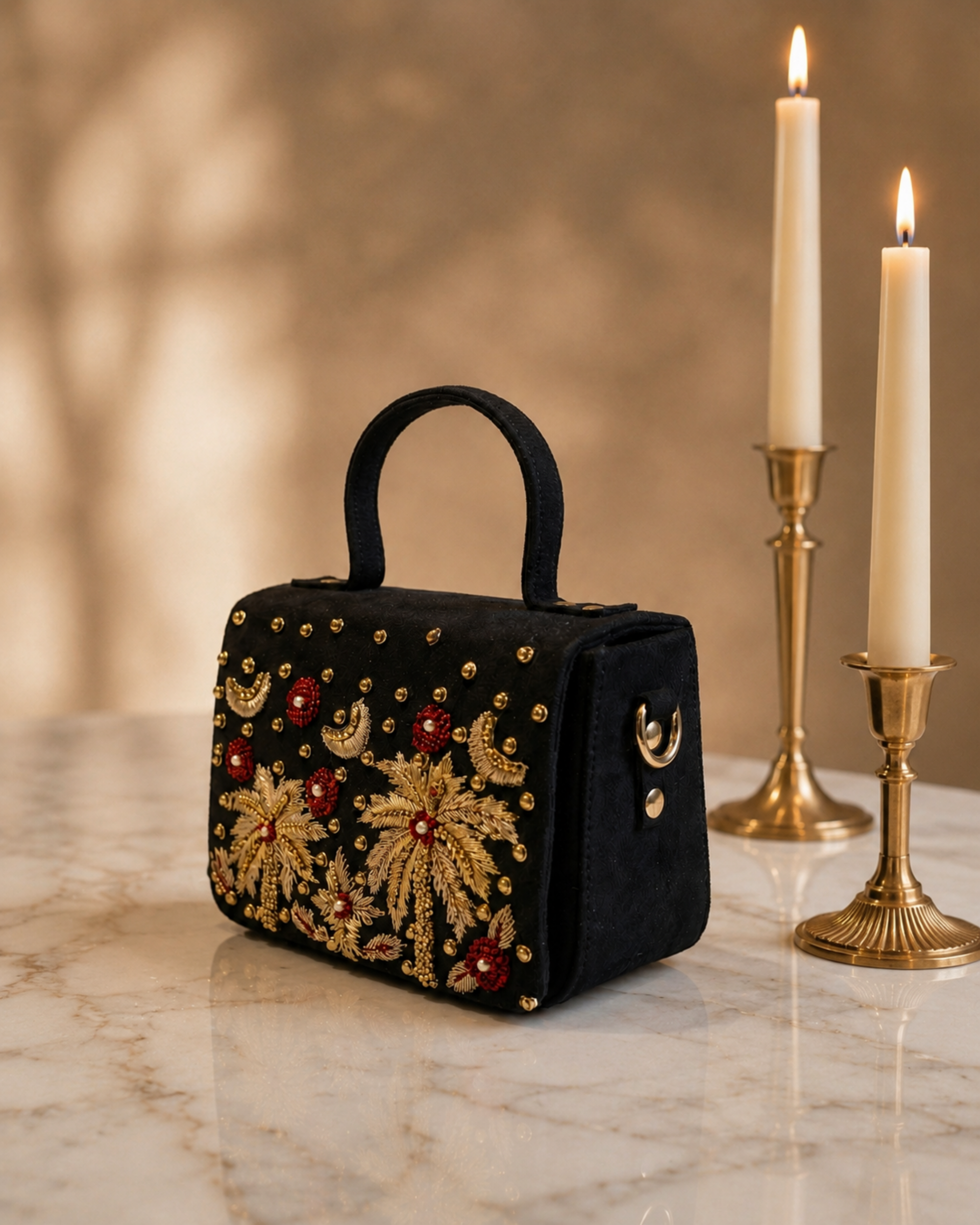 Side view of House of Shine Tropical Moonbeam Satchel in black velvet showing structured silhouette and gold zardozi embroidery detail, styled with brass candle holders
