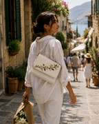 Woman carrying the Zagara ivory hand-embroidered shoulder bag on a sunlit Italian street