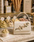 Zagara hand-embroidered ivory floral bag styled inside a traditional Italian gelateria