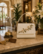 Zagara structured ivory floral bag with gold hardware styled at the concierge of an elegant Italian hotel