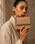 Model in beige blazer holding Liquid Gold crystal-embellished mini top-handle bag by House of Shine up near her face, gold hoop earrings, gold-polished hardware, saffiano exterior, Bijou Edit.