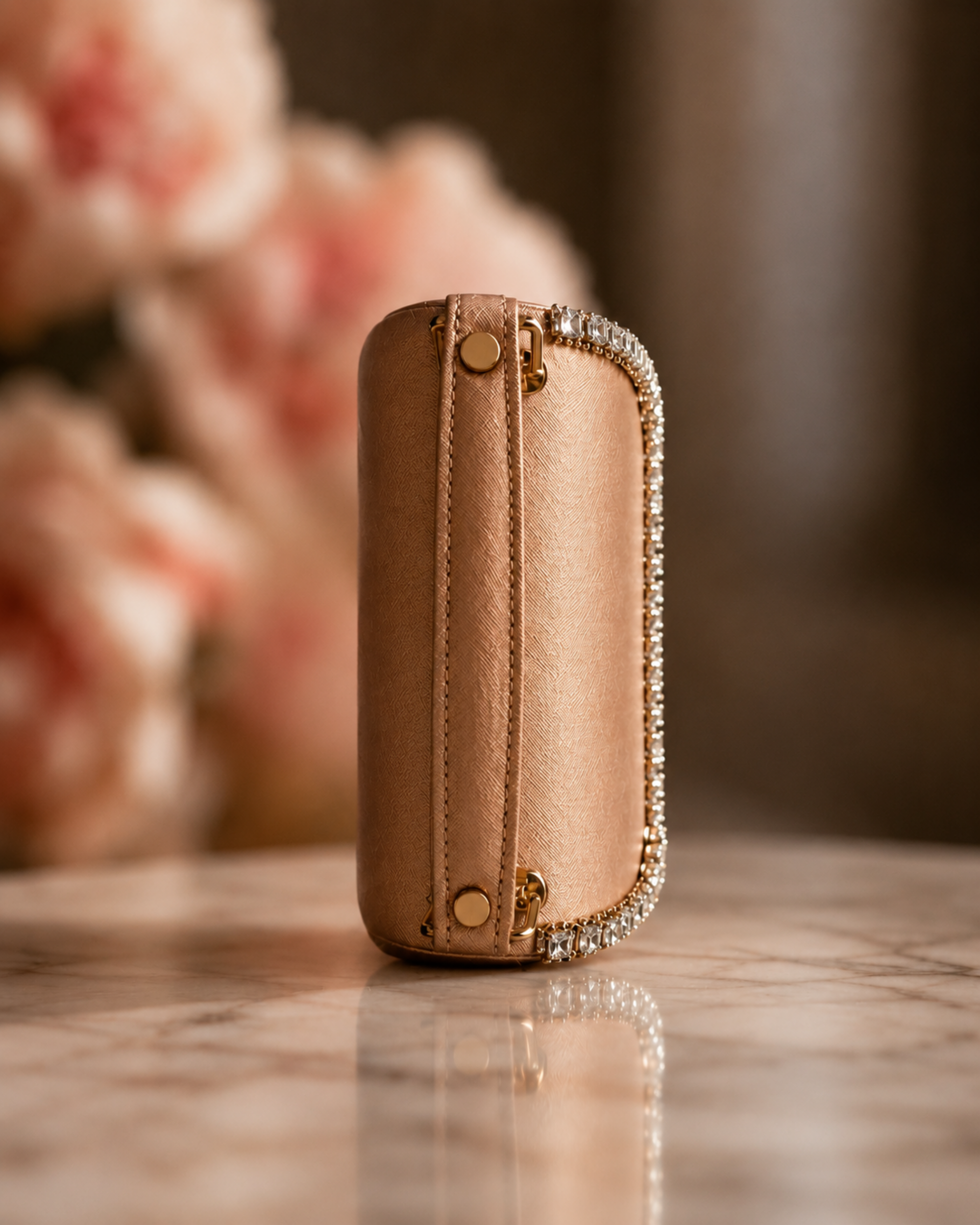 Side profile of Liquid Gold crystal-embellished mini top-handle bag by House of Shine, showing saffiano texture and crystal trim against blush peonies, gold-polished hardware, Bijou Edit.