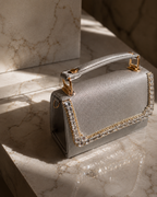 Silver Moonlit crystal-embellished mini top-handle bag by House of Shine, angled detail shot on marble surface, gold-polished hardware and hand-set crystal trim, saffiano exterior, Bijou Edit.
