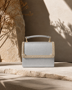 Silver Moonlit crystal-embellished mini top-handle bag by House of Shine, styled on sandstone steps with dried golden botanicals, gold-polished hardware, saffiano exterior, Bijou Edit.