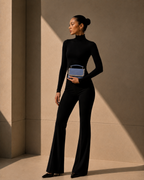 Model in black turtleneck and flared trousers carrying Something Blue crystal-embellished mini top-handle bag by House of Shine at her side, gold hoop earrings, gold-polished hardware, saffiano exterior, Bijou Edit.
