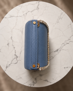 Side profile of Something Blue crystal-embellished mini top-handle bag by House of Shine, overhead view on marble showing saffiano texture and crystal trim, gold-polished hardware, Bijou Edit.