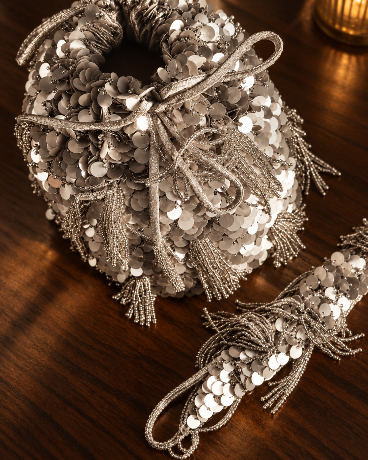 Close-up of the silver Twilight Dust potli’s drawstring opening, sequins and beaded tassels, with its embellished strap alongside.